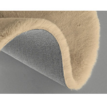 Detalj av en beige matta med lurvig ovansida och textilbaksida