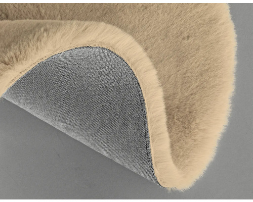 Detalj av en beige matta med lurvig ovansida och textilbaksida