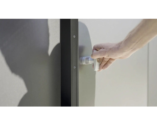 En hand stänger en metalldörr med ett vridlås.