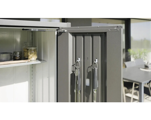 Öppet trädgårdsskåp med hyllor och grillredskap på dörren