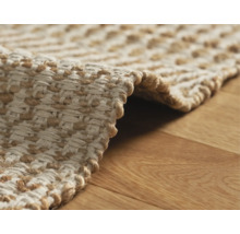 Detaljvy av en flätad matta i naturfiber på ett trägolv