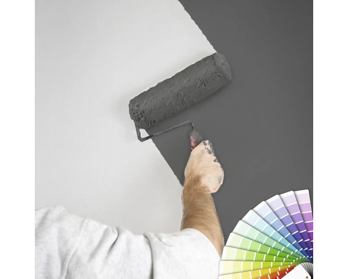 "En person målar en vägg med en färgroller
