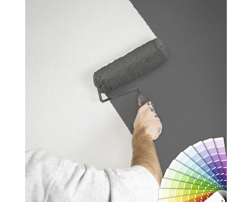 "En person målar en vägg med en färgroller