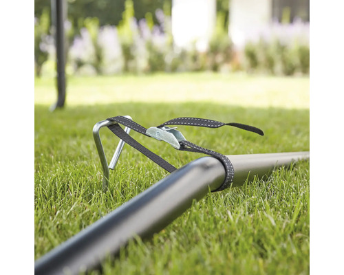 Fästning av lusthus med pinnar och spännband i gräset