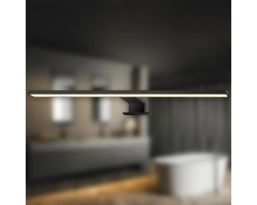 Badrum med en svart LED-vägglampa ovanför ett handfat och ett badkar