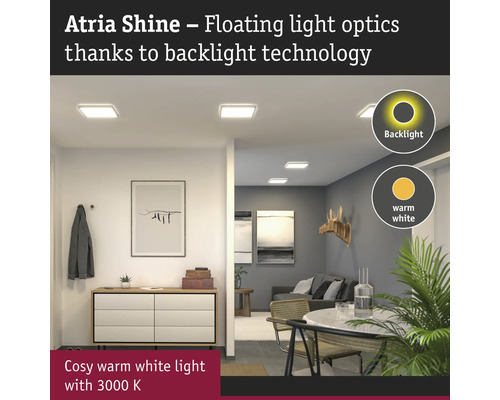 Hall och vardagsrum med taklampor som har bakgrundsbelysning och avger ett varmvitt ljus.