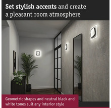 Hall med vägglampor, spegel och krukväxt för en behaglig atmosfär.