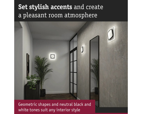 Hall med vägglampor, spegel och krukväxt för en behaglig atmosfär.