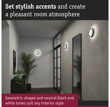 Hall med vägglampor, spegel och krukväxter för en behaglig atmosfär.