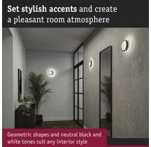 Hall med två runda vägglampor, spegel och krukväxter