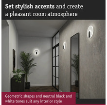 Hall med två runda vägglampor, en spegel och en krukväxt.