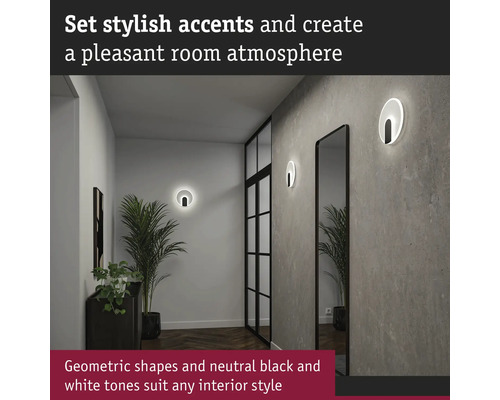 Hall med två runda vägglampor, en spegel och en krukväxt.