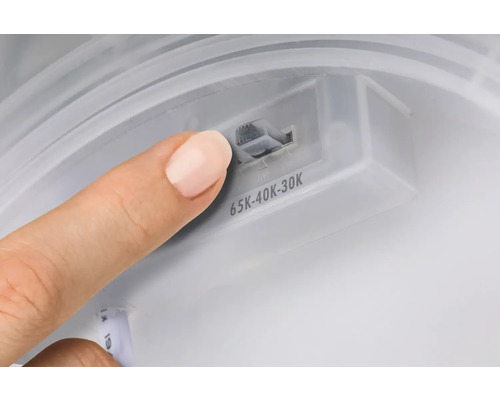 Ett finger justerar ljusets färgtemperatur på lampan