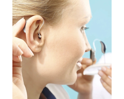Kvinna sätter in hörapparat i örat
