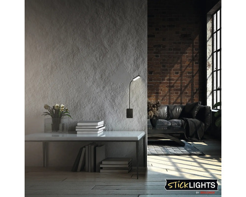 Vardagsrum med bord, böcker, blomvas och en monterad vägglampa