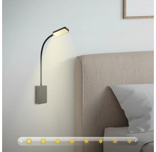 Vägglampa med flexibel arm bredvid en säng