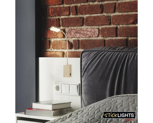 Väggmonterad läslampa bredvid sängen mot en tegelvägg.
