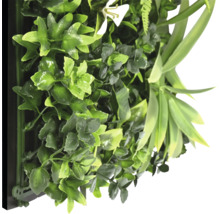 Konstgjord växtvägg med olika gröna blad och en vit blomma