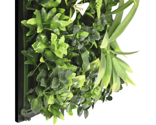 Konstgjord växtvägg med olika gröna blad och en vit blomma