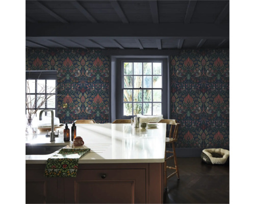 Kök med blommig tapet, köksö och fönster.