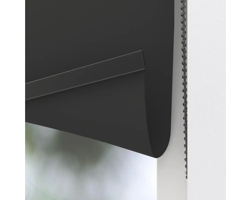 Detaljbild av en svart rullgardin med kedjedrag för fönsterförmörkning.