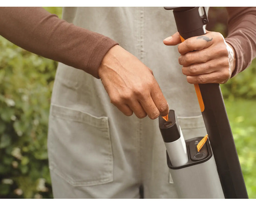 Batteridriven grästrimmer med laddare i bruk