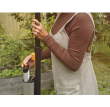 En person sätter i ett batteri i ett trädgårdsredskap.