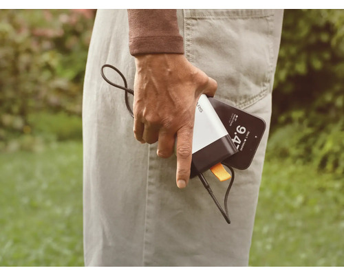 En person håller i en mobiltelefon och en powerbank.