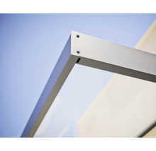 Detaljbild av hörnfogen på ett entrétak med metallram och glaselement.