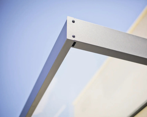 Detaljbild av hörnfogen på ett entrétak med metallram och glaselement.