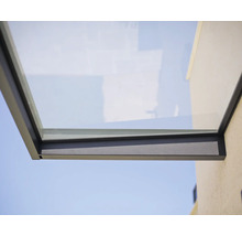 Modernt entrétak av glas med mörkgrå metallram monterat på en fasadvägg.