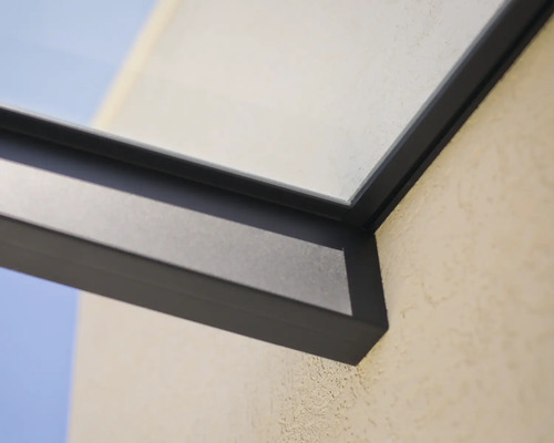 Detalj av en mörk aluminiumram för ett altantak med glaselement på en yttervägg.