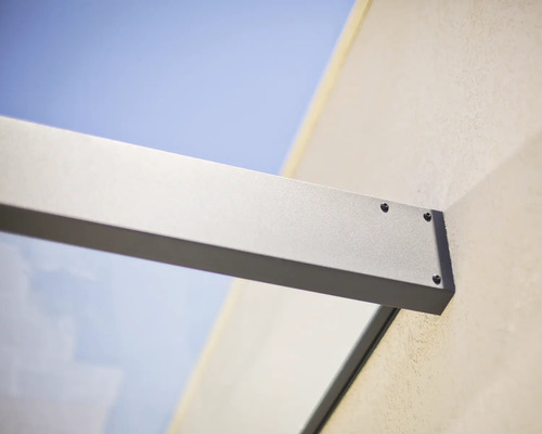 Vägginfästning av en glastaksprofil i aluminium med synliga skruvar.