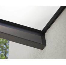 Detaljvy av ett terrassöverdrag med aluminiumprofiler och en glasskiva på en strukturerad vägg.