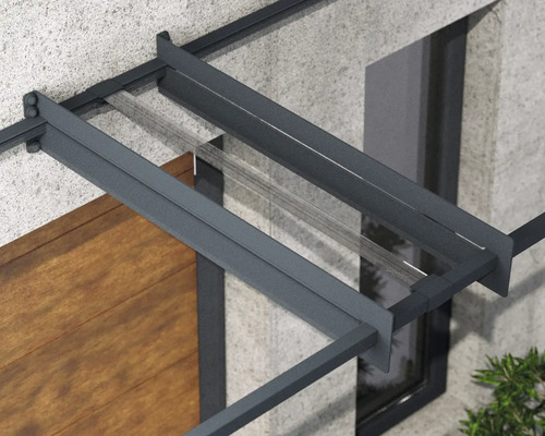 Detaljvy av ett entrétak med antracitfärgad aluminiumram och transparent glastak på en husvägg.