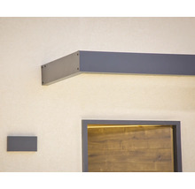 Modernt entrétak i antracit med integrerad LED-belysning ovanför en dörr i trälook och matchande vägglampa.