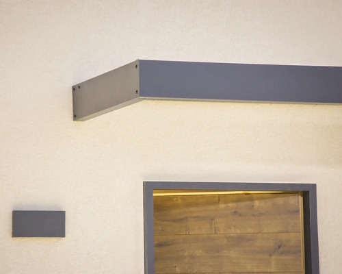 Modernt entrétak i antracit med integrerad LED-belysning ovanför en dörr i trälook och matchande vägglampa.