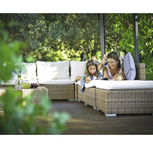 Mor och dotter kopplar av på en rottingsoffa i trädgården under en paviljong.