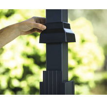 Hand monterar svart stolplock på staketstolpe