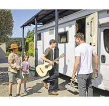 Familj med gitarr under ett terrasstak bredvid en husbil