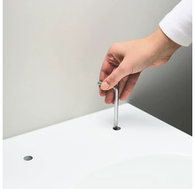 En person för in en insexnyckel i ett hål i en vit yta