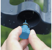 Närbild av en hand som sätter in ett munstycke i en grässpridare.