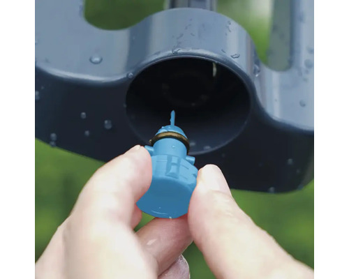 Närbild av en hand som sätter in ett munstycke i en grässpridare.