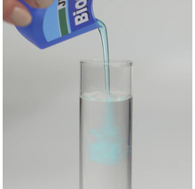 Blå vätska hälls från en flaska i ett provrör fyllt med vatten för att visa blandningsprocessen.