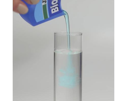 Blå vätska hälls från en flaska i ett provrör fyllt med vatten för att visa blandningsprocessen.