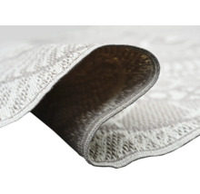 Närbild på en slätvävd matta med geometriskt mönster som visar vävstrukturen och baksidan av det vikta hörnet.