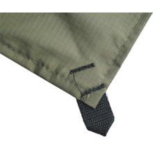 Detaljvy av en grön täckpresenning av väv med förstärkt hörn och en svart fästögla.