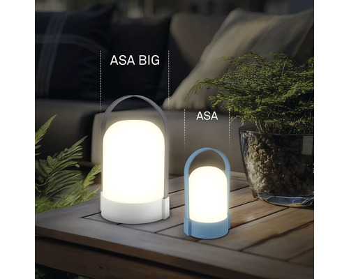 Två moderna LED-lyktor ASA BIG och ASA på ett träbord, stämningsfull utomhusbelysning med växter och soffa i bakgrunden.