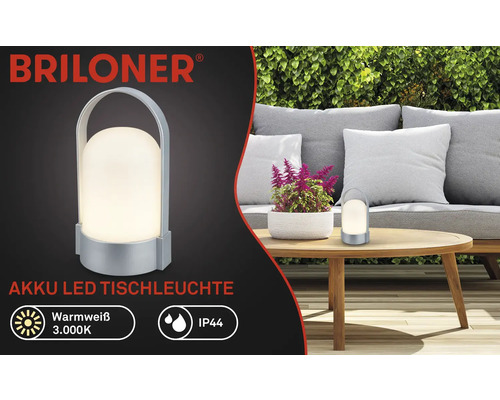 Briloner Logo, batteridriven LED-bordslampa, varmvit 3000 kelvin, IP44, bärbar med bärhandtag, i en trädgård på ett träbord.