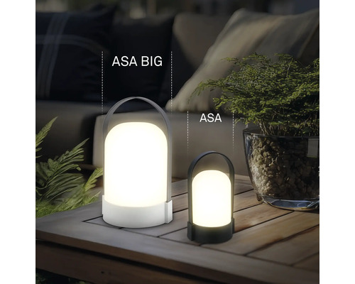 Två bärbara LED-bordslampor ASA BIG och ASA i olika storlekar på ett träbord utomhus med växter och stoppade möbler.
